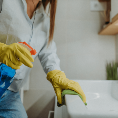 GettyImages-1364505556 A cleaning professional sprays and wipes down a sink.