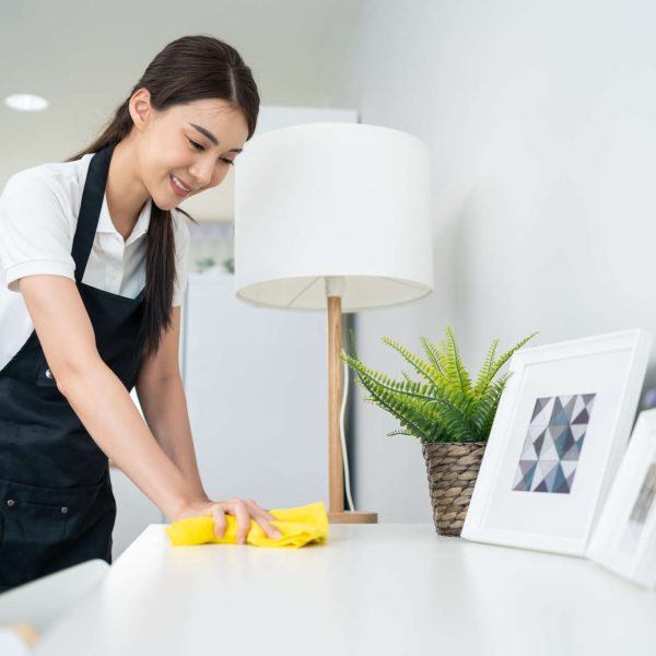 hero-6.jpg A cleaning professional wipes down a desk in a modern home.